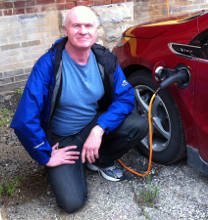 Photo of Mark next to his plugged in Volt EV