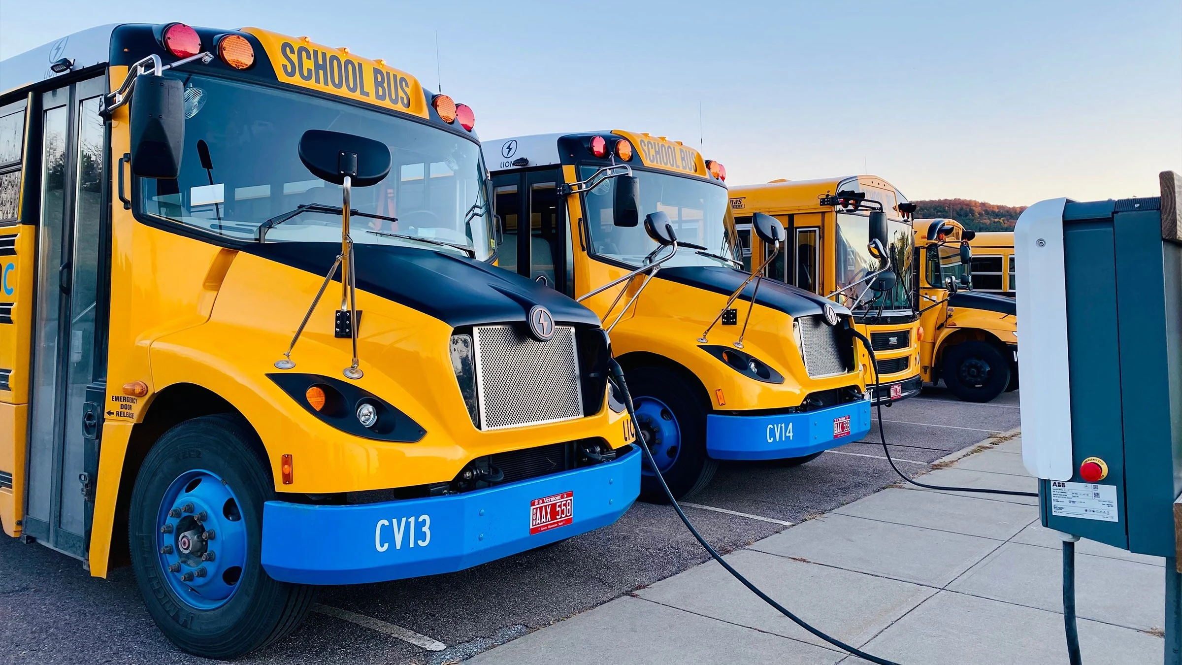 A fleet of electric school busses plugged into a municipal EV charging station.