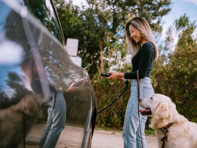 A woman charging her electric vehicle using a public EV charger.