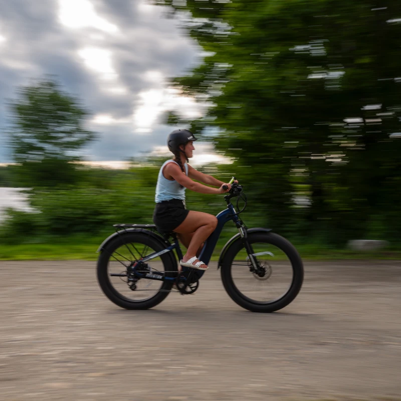 A woman riding an e-bike on a gravel road.