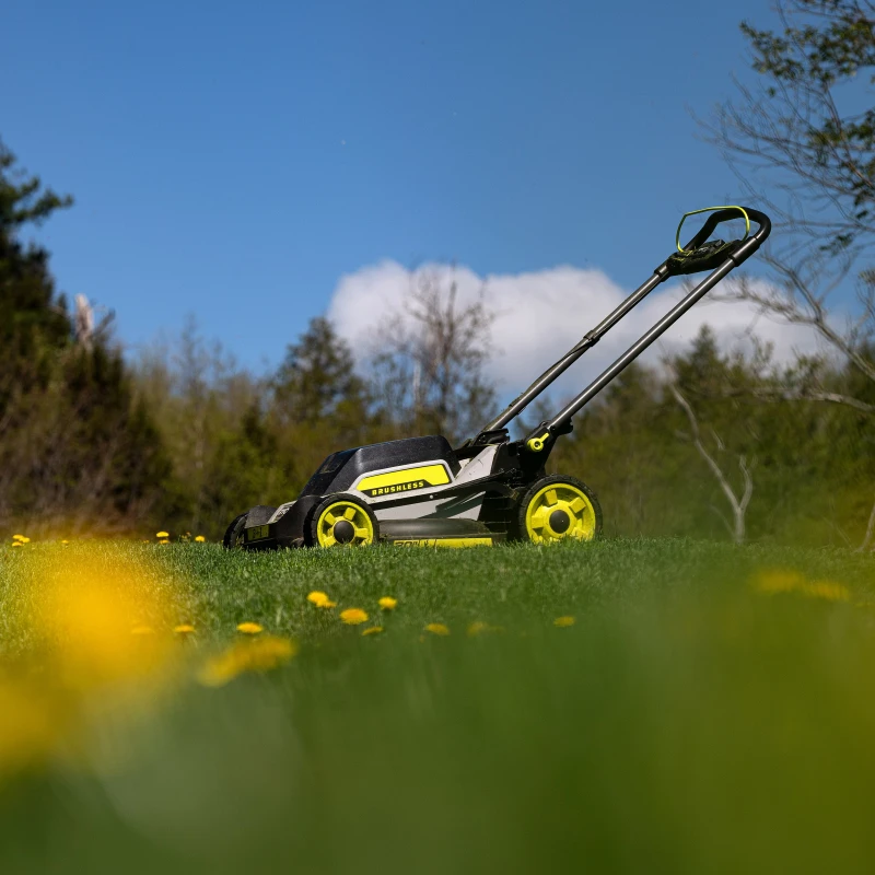 An electric lawn mower sitting in an open yard.